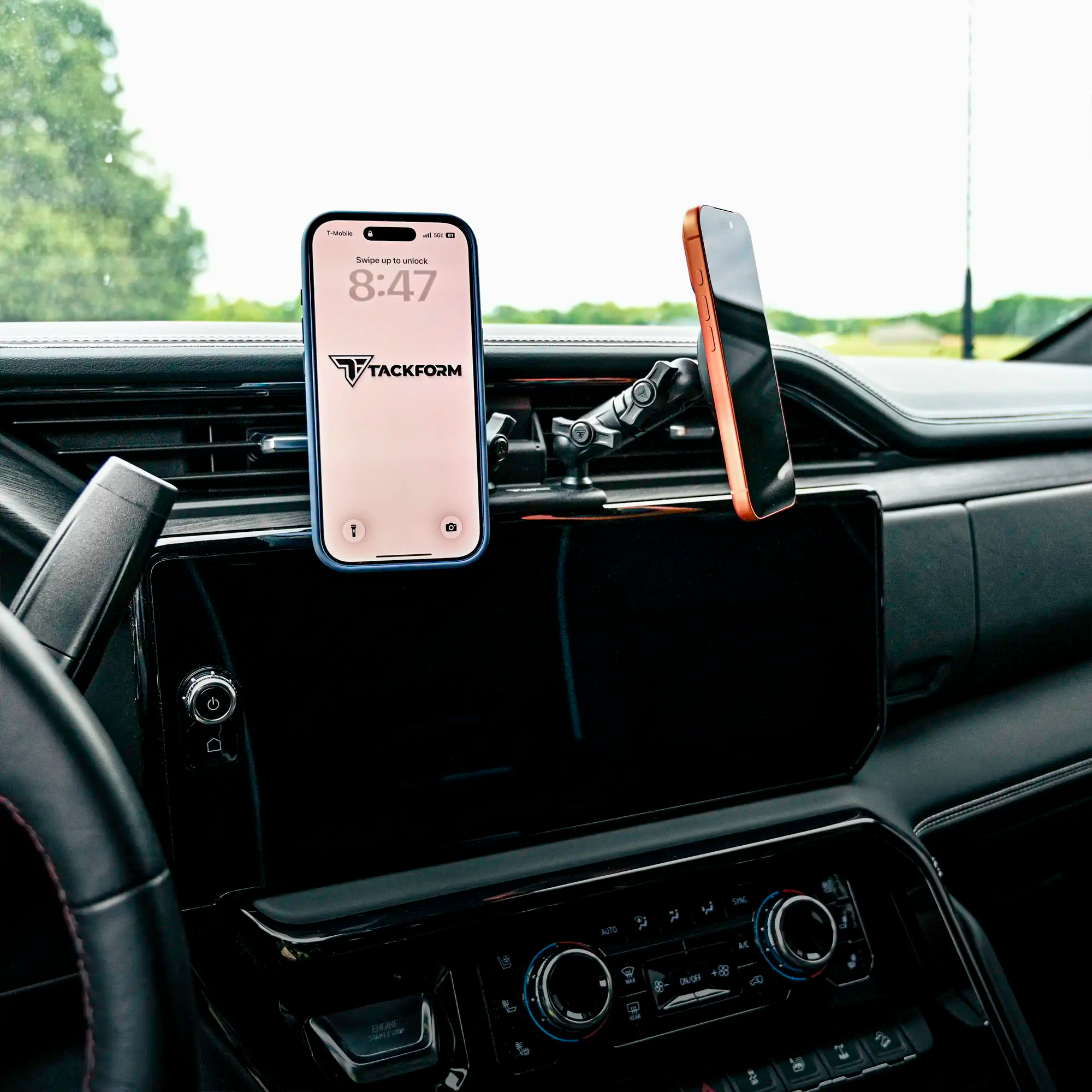 Two iPhones mounted onto black Tackform MagSafe-compatible magnetic phone holders attached to all-metal dash clip installed in a GMC Sierra